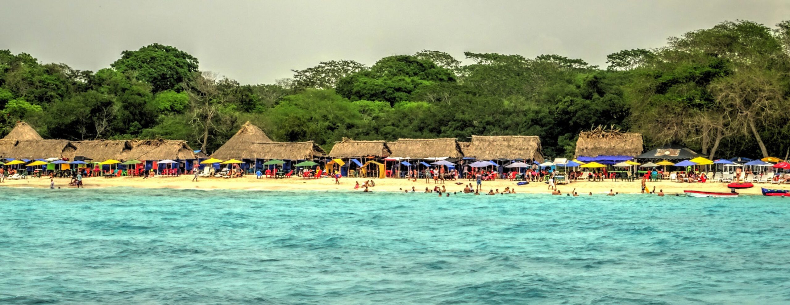 a group of people on a beach with umbrellas.