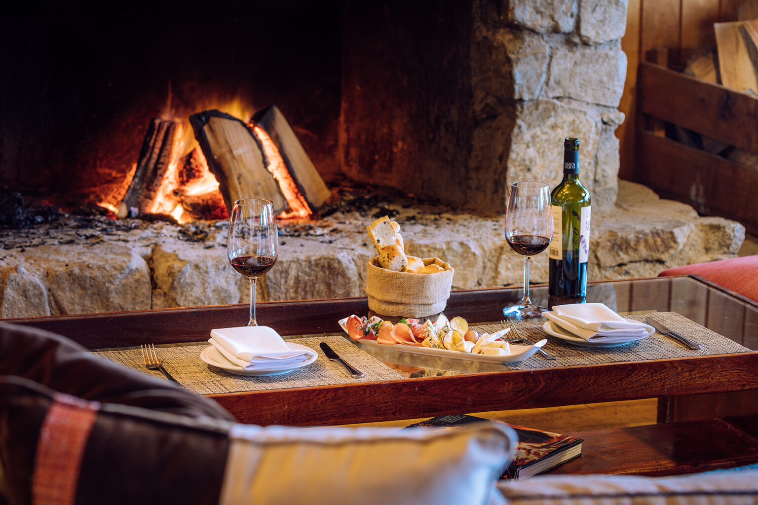 Table in front of fireplace with wine and bread