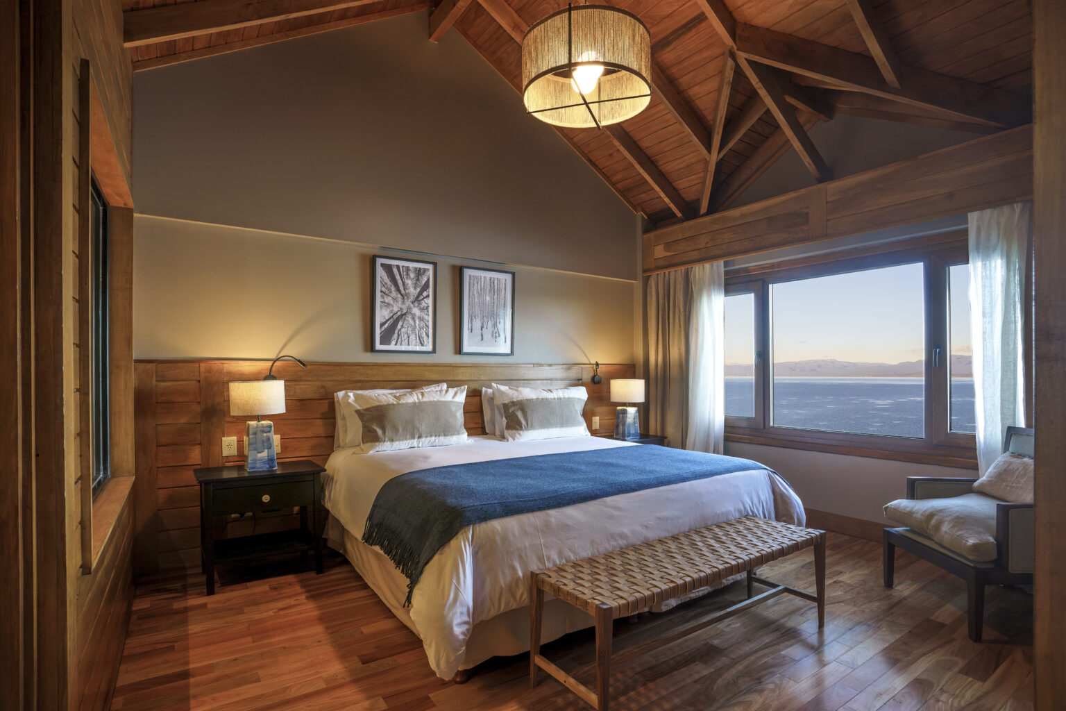 Hotel room with bed and window overlooking water and mountains