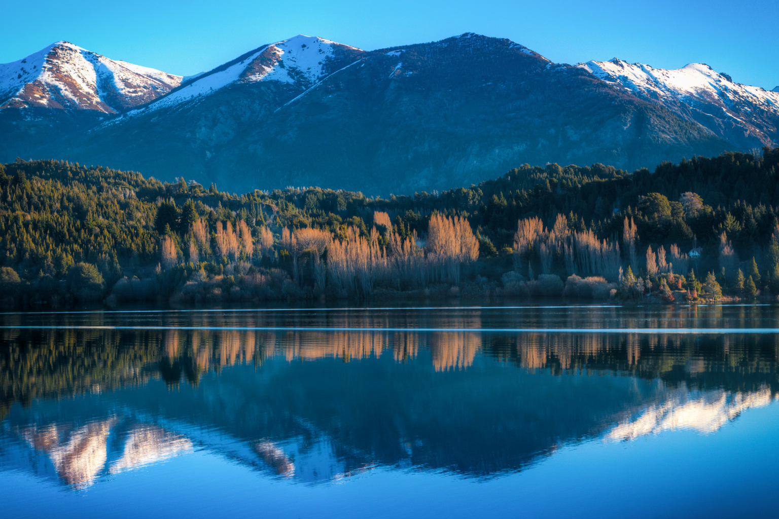 Snow capped mountains reflecting on calm lake