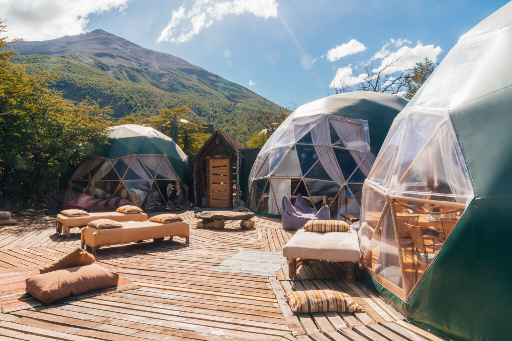 Three Eco Camp domes on a sunny day with an outdoor lounge area in the foreground
