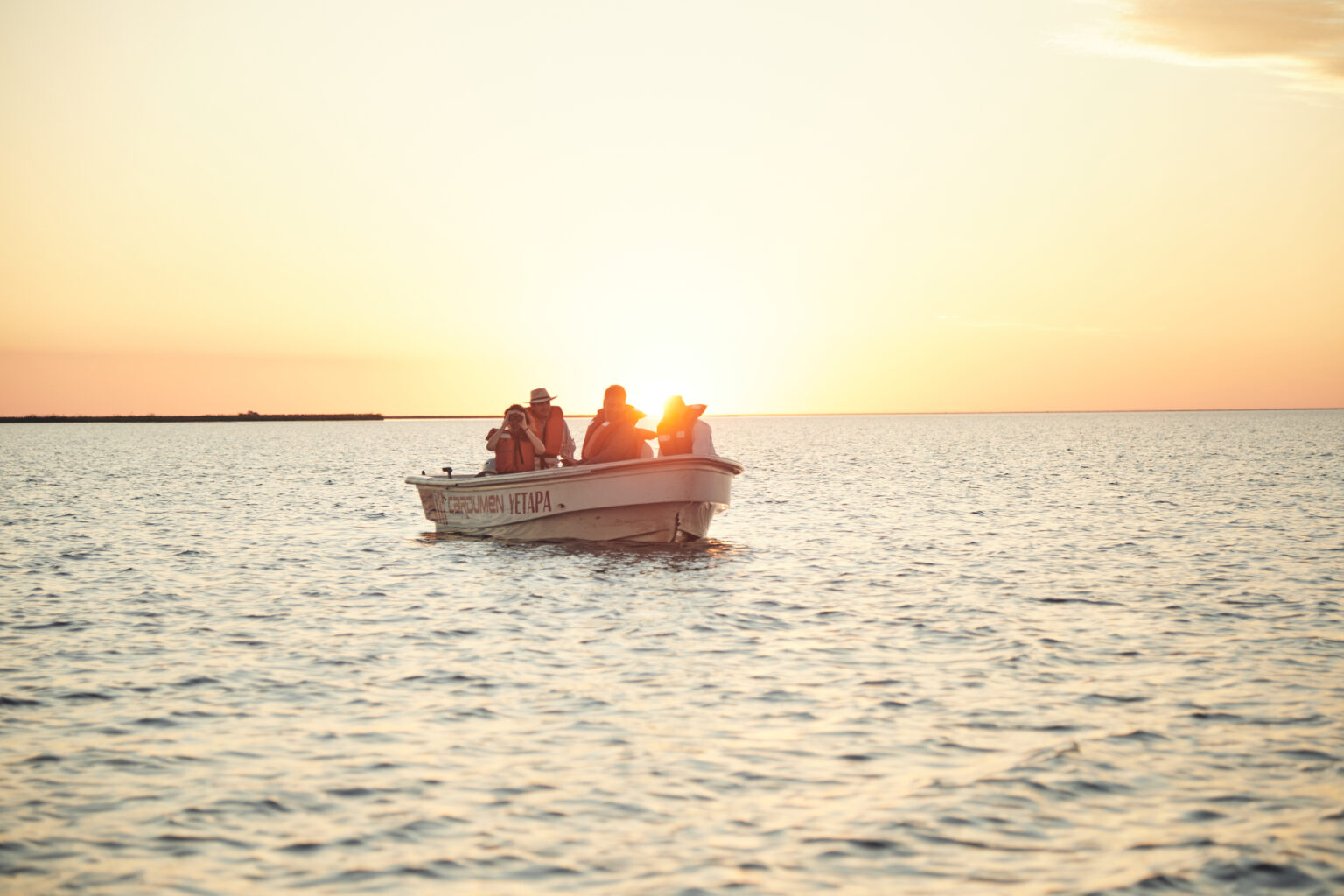 Small boat with five people during sunset