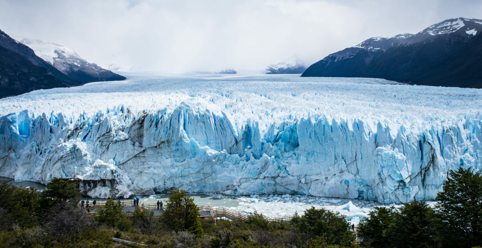 Large blue glacier between dark mountains