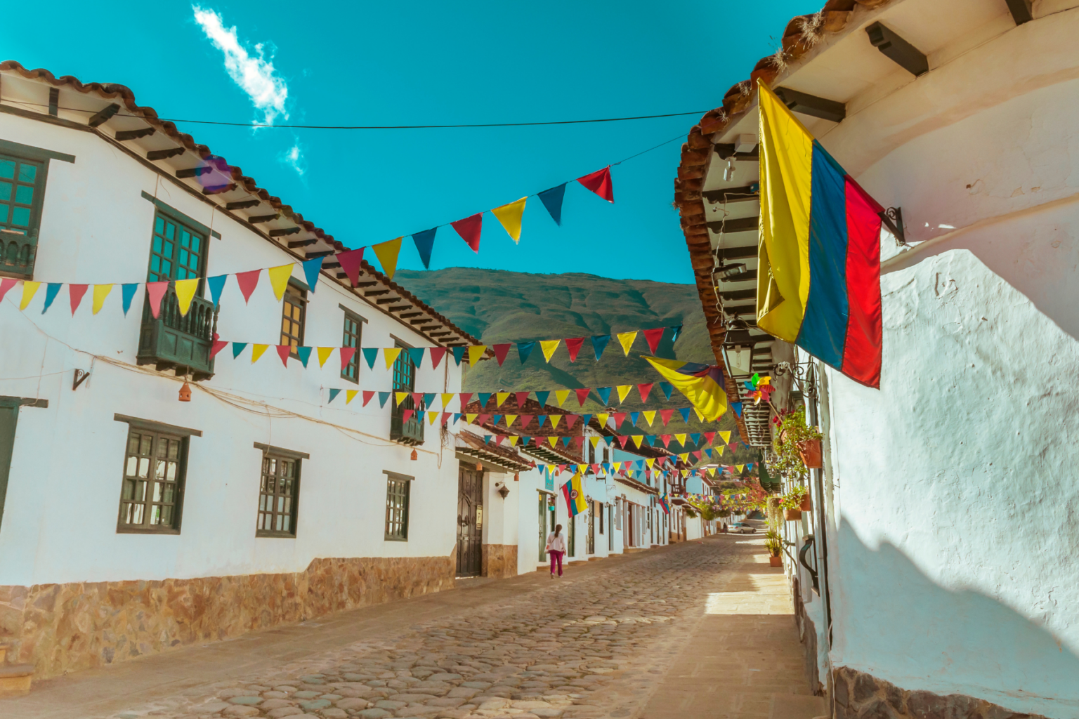 Cobblestone street with white buildings and flags