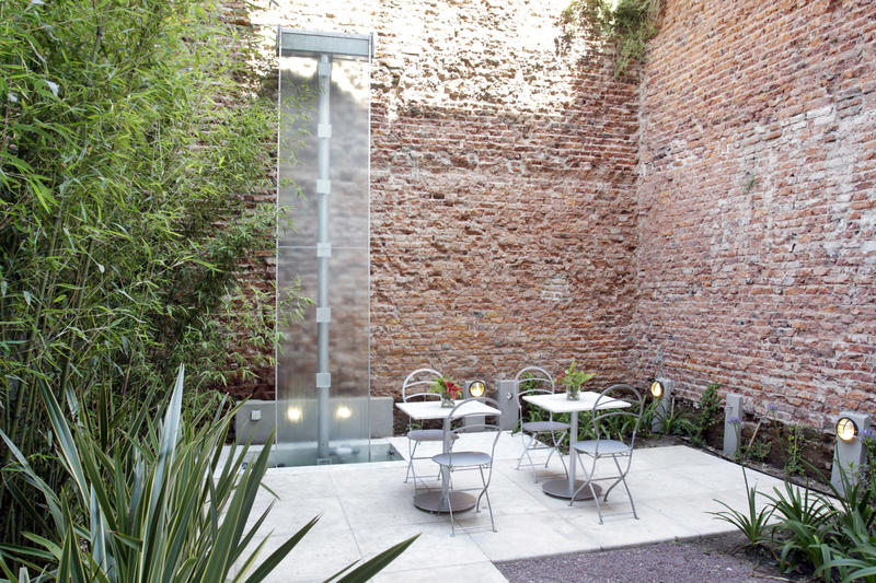 Courtyard with brick walls and plants and two breakfast tables