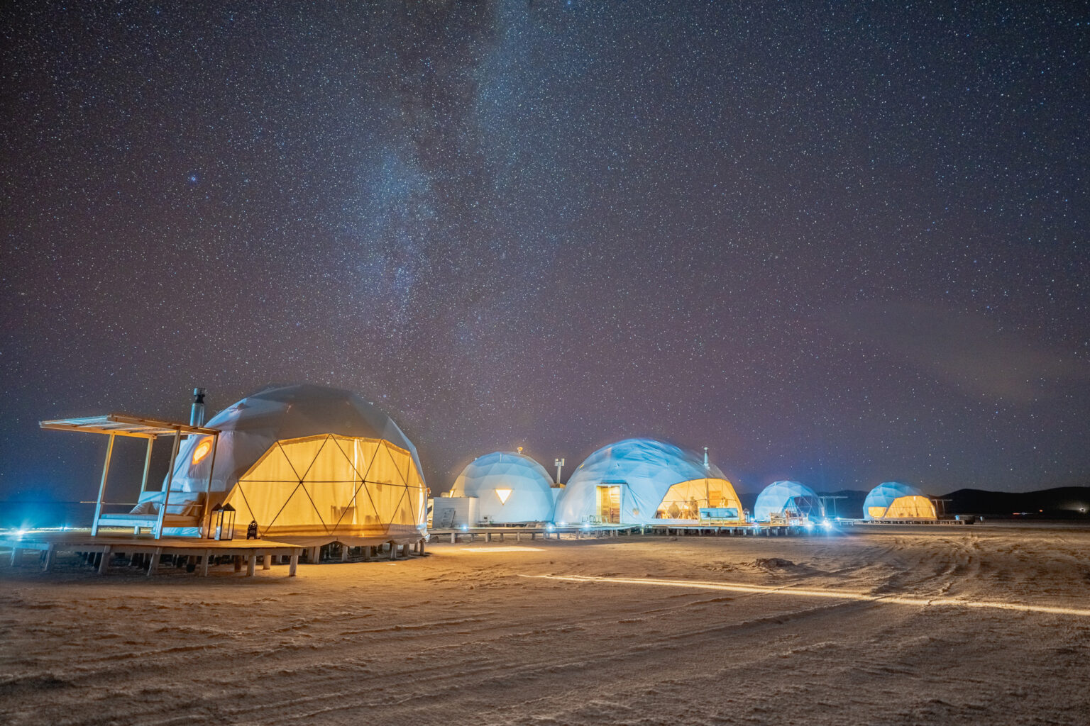 White domes with large windows on salt flat at night