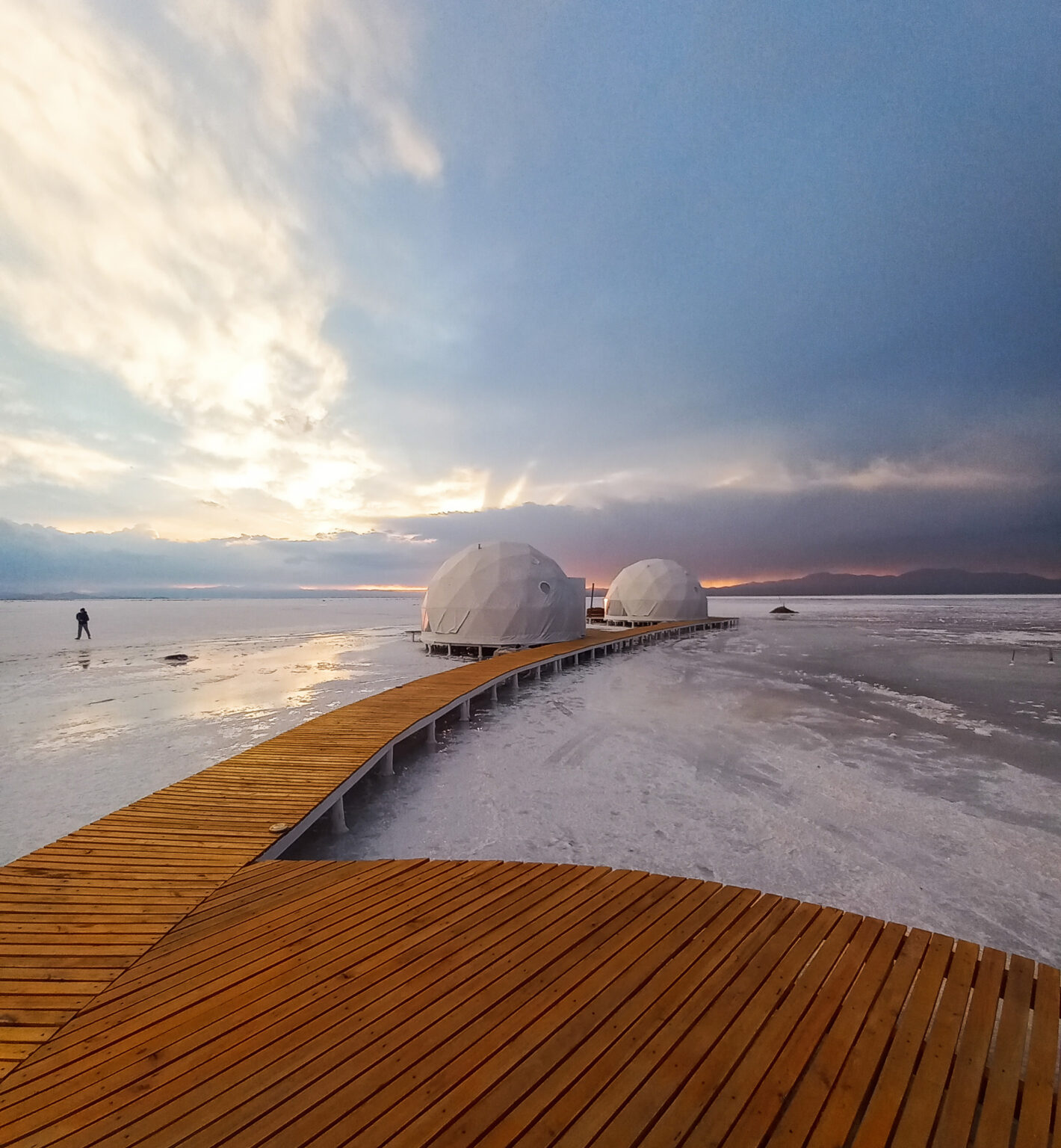 Wooden walkway leading to two white domes on salt flats