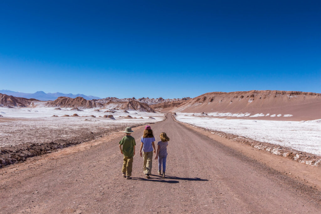 A trio of children walk along a road deep in the Atacama Desert
