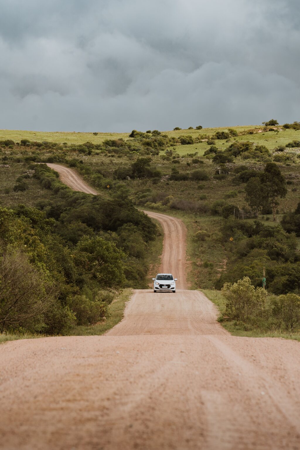 A car drives through rural Uruguay along an unpaved country road.