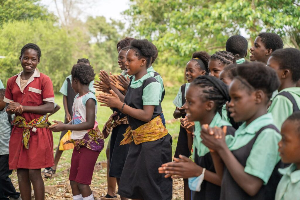A group of school girls singing and clapping