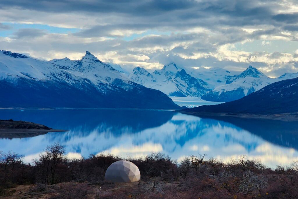 Geodesic dome by a lake with snowy mountains in El Calafate, Argentina