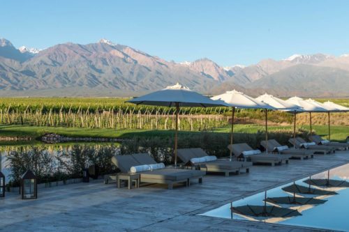 pool deck with chairs and umbrellas with vineyards and mountains in the background