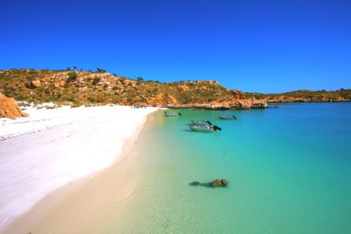 Small motorboats anchor on a deserted beach for a picnic in the Kimberley