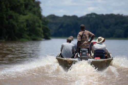 Sangha Lodge Congo Basin safari Odzala guests and guide cruising down river in small motor boat