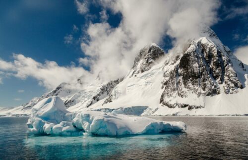 aqua icebergs floating in front of snow-capped mountains on the Antarctic Peninsula