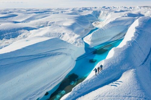 guests hiking along a snowy ridge overlooking aquamarine waters in Antarctica