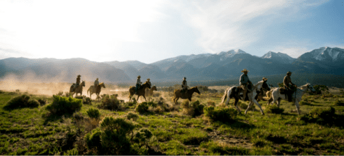 Group on horseback riding in Colorado in front of mountains