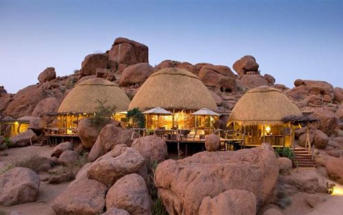 camp built into the red desert rocks in namibia