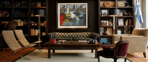 Black leather couch and wooden coffee table in front of painting