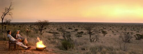 sunset over the Kalahari and a family sitting by a campfire