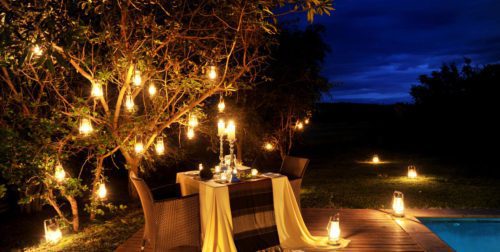 candlelit dinner in the bush beneath a tree filled with kerosene lanterns